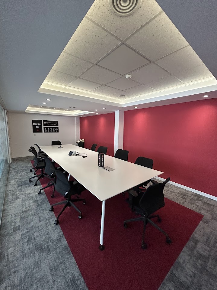 Sala de reuniones con mesa alargada y pared destacada en rojo
